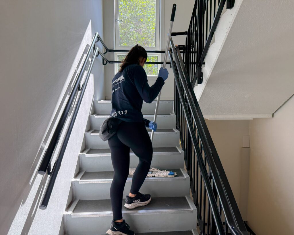Ansatt mopper trappen i en boligblokk som del av fast trappevask