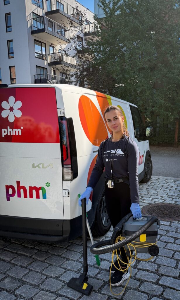 Ansatt fra PHM klar for renhold i et boligområde, med industristøvsuger ved siden av firmabilen